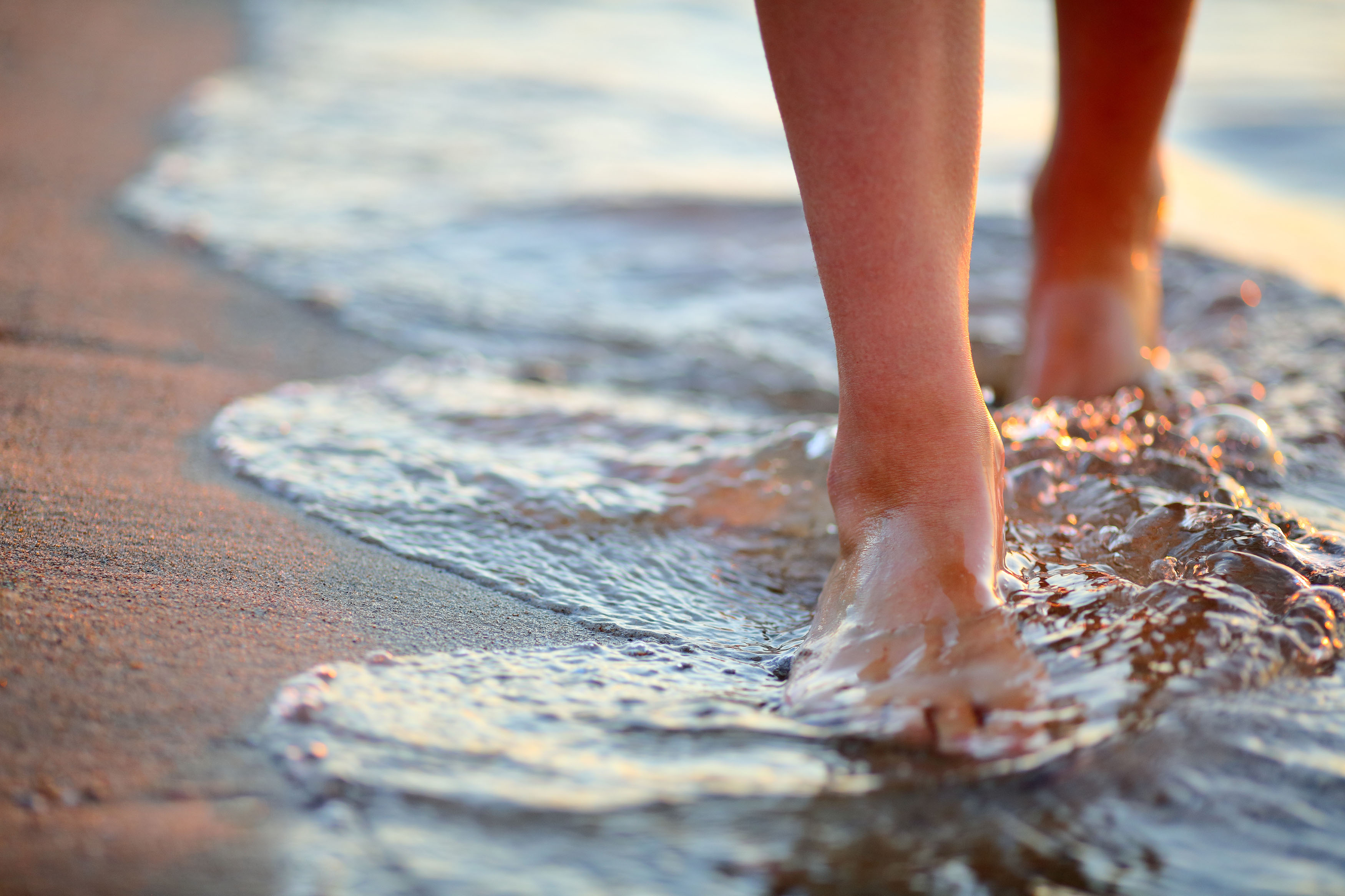 Female feet step on the sea wave